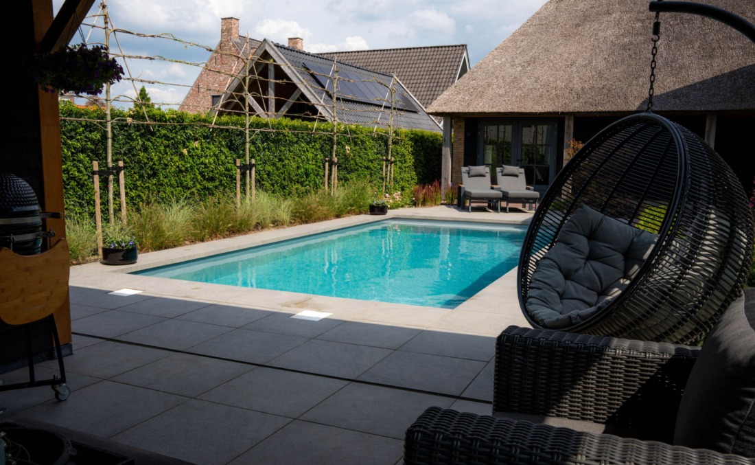 Een prachtige tuin met luxe BBQ, een langwerpig zwembad van HDPE, twee ligbedden en een hangstoel