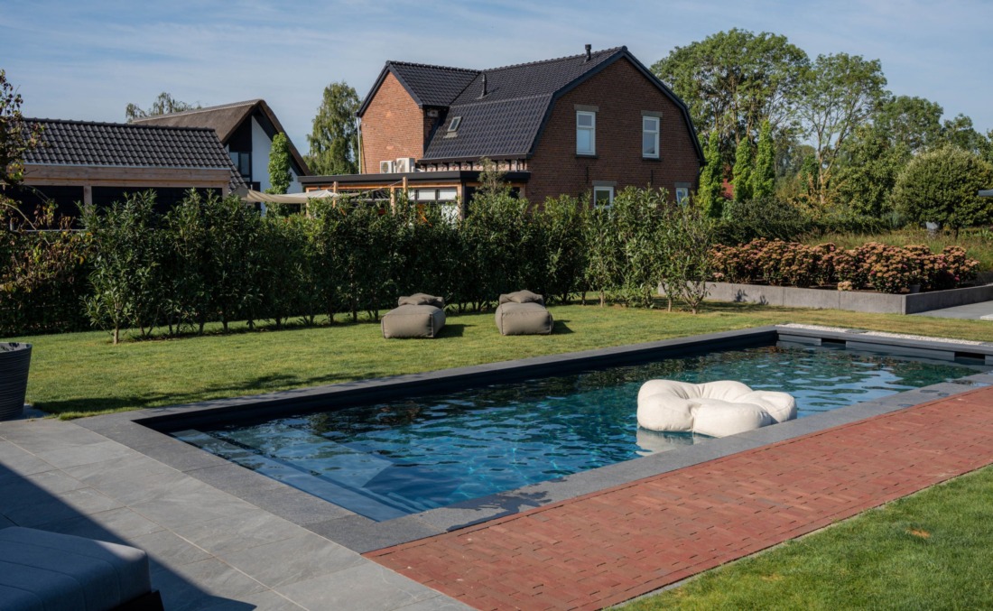 Skimmerzwembad met inlooptrap en zitgedeelte in een groene omgeving