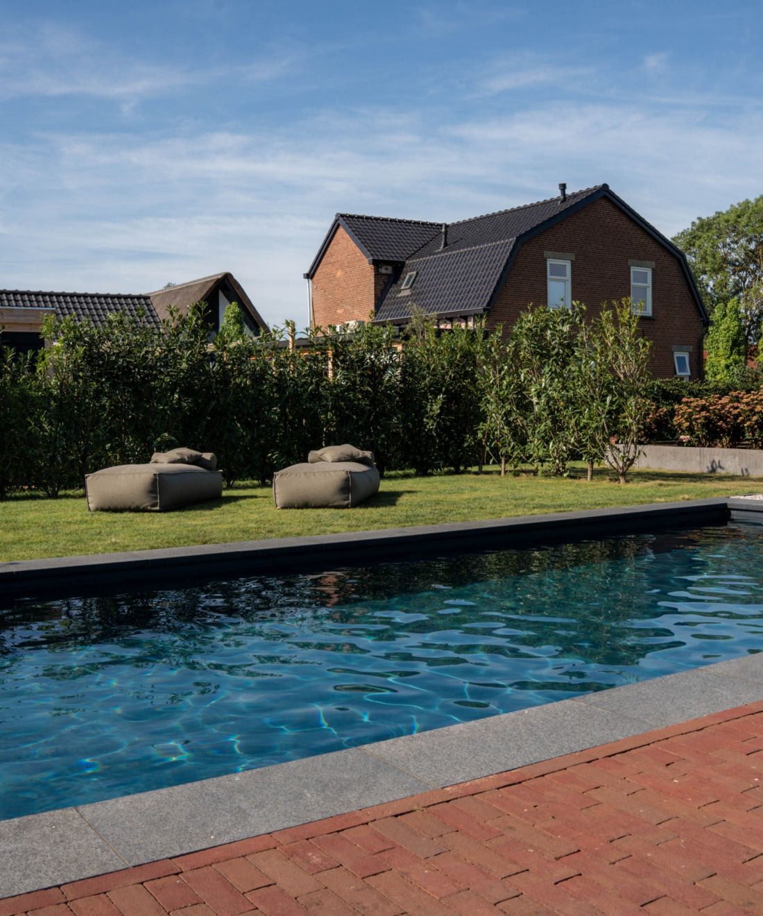 Ruim rechthoekig zwembad in een groene omgeving met twee luxe zitzakken van Zaque