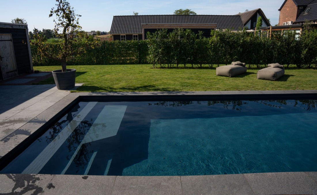 Zwembad met wat donkerder blauw gekleurd water, met inlooptrap en zitgedeelte.