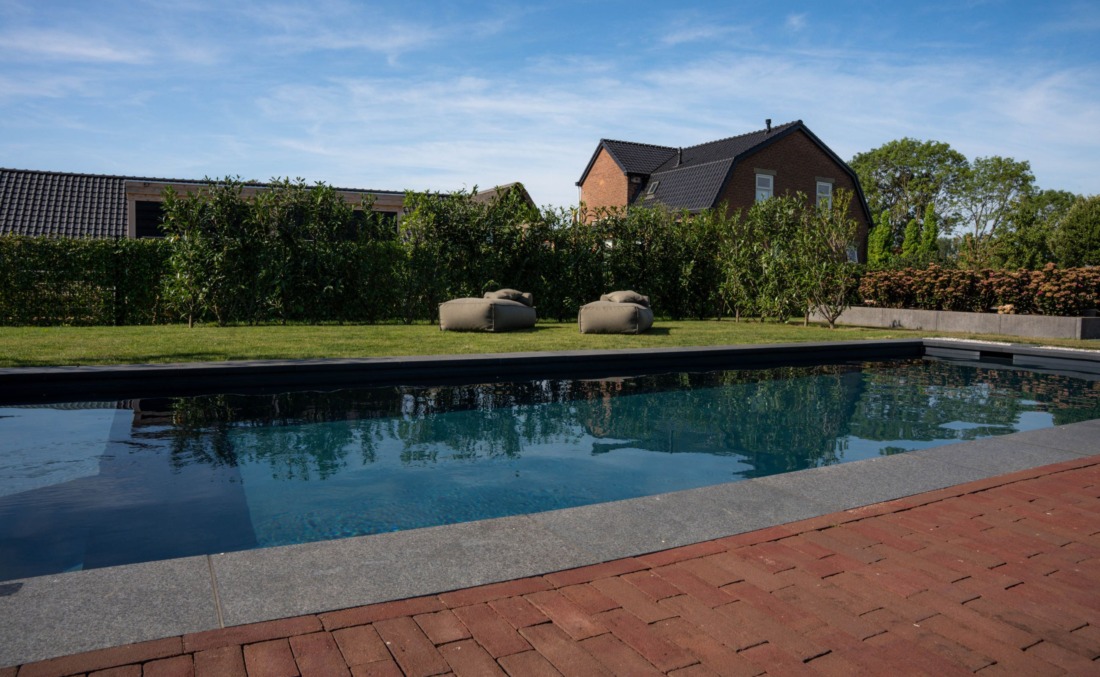 Luxe zwembad met wat donkerder gekleurd water, aan de zijkant liggen twee ligzakken