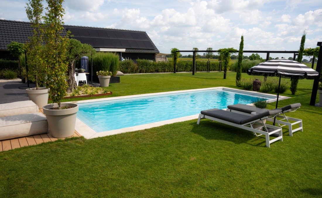 HDPE buitenzwembad met twee ligbedden en een parasol met witte en zwarte strepen