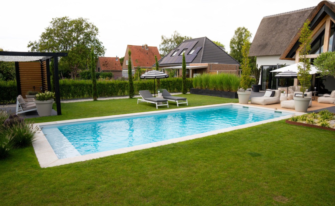 Langwerpig buitenbad met skimmers, een zitgedeelte en brede inlooptrap