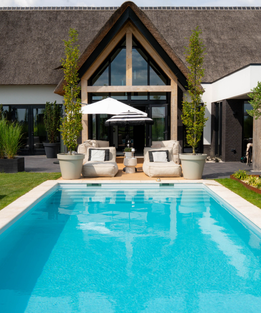 Prachtig wit huis met rieten kap met in de achtertuin in langwerpig HDPE zwembad en diverse ligstoelen