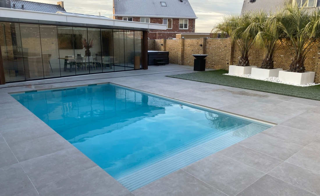 Skimmerzwembad met inlooptrap in luxe tuin met drie grote palmbomen