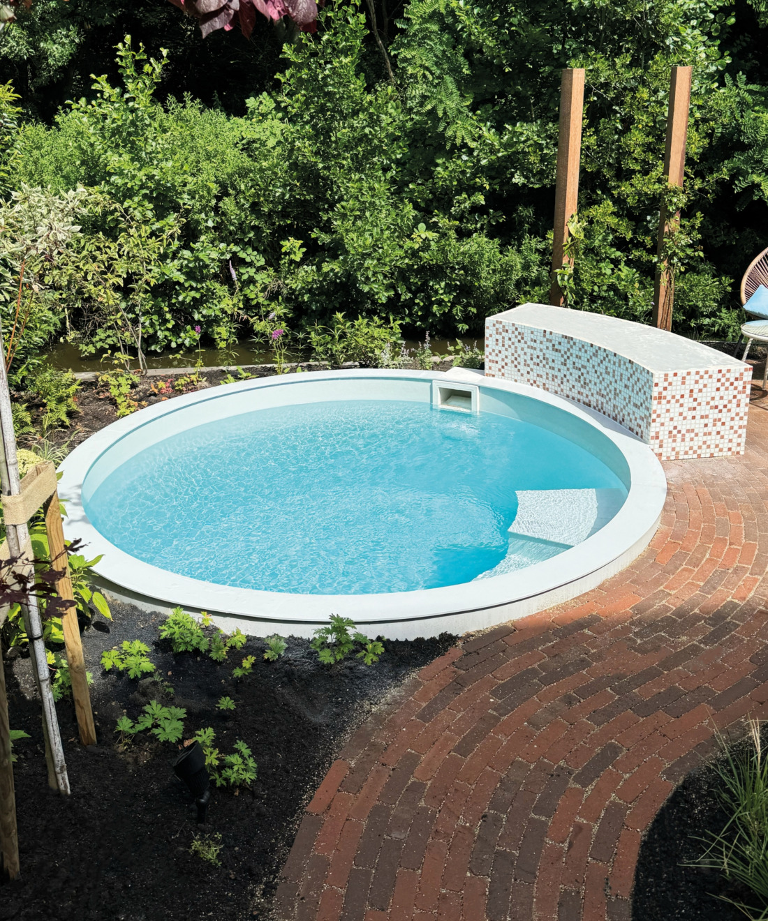 Klein rond zwembad omringd door groene planten