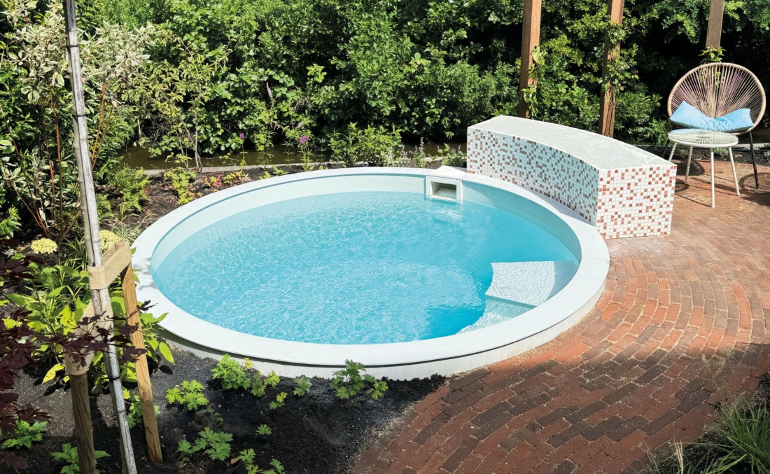 Klein rond zwembad omringd door groene planten