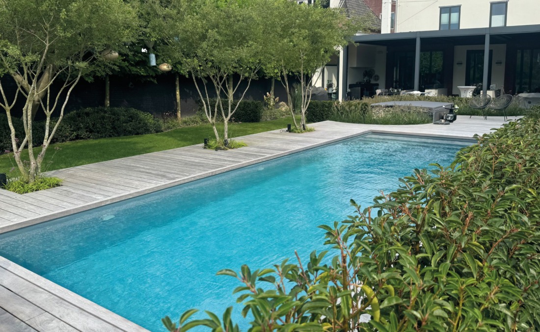 Strak zwembad design in groene tuin omringd door houten vloer