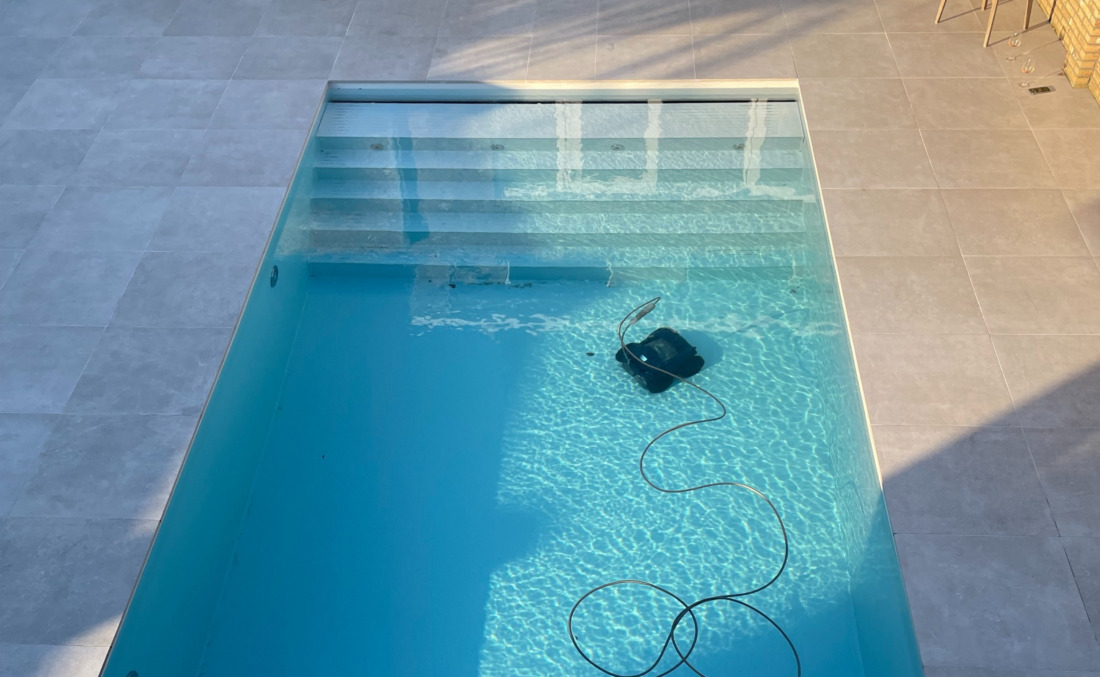 Zwembadstofzuiger in een wit HDPE zwembad met inlooptrap over de hele breedte