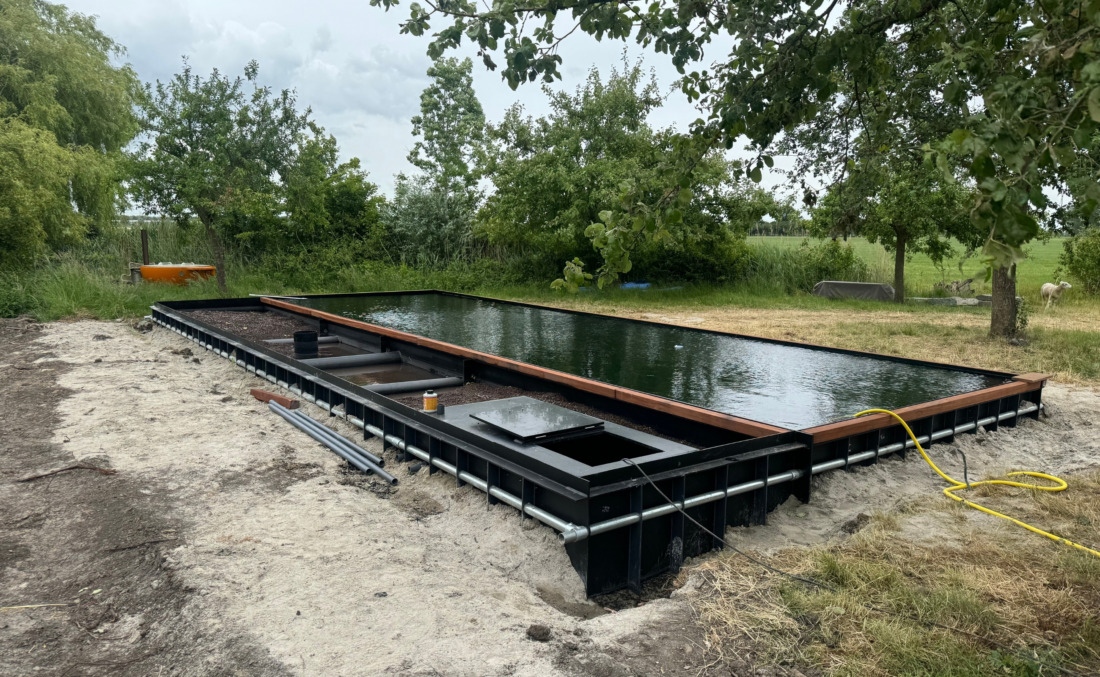 Casco plaatsing van een zwart HDPE zwembad van JDL, waarbij de stevige externe ribbenconstructie en het leidingwerk goed zichtbaar zijn.
