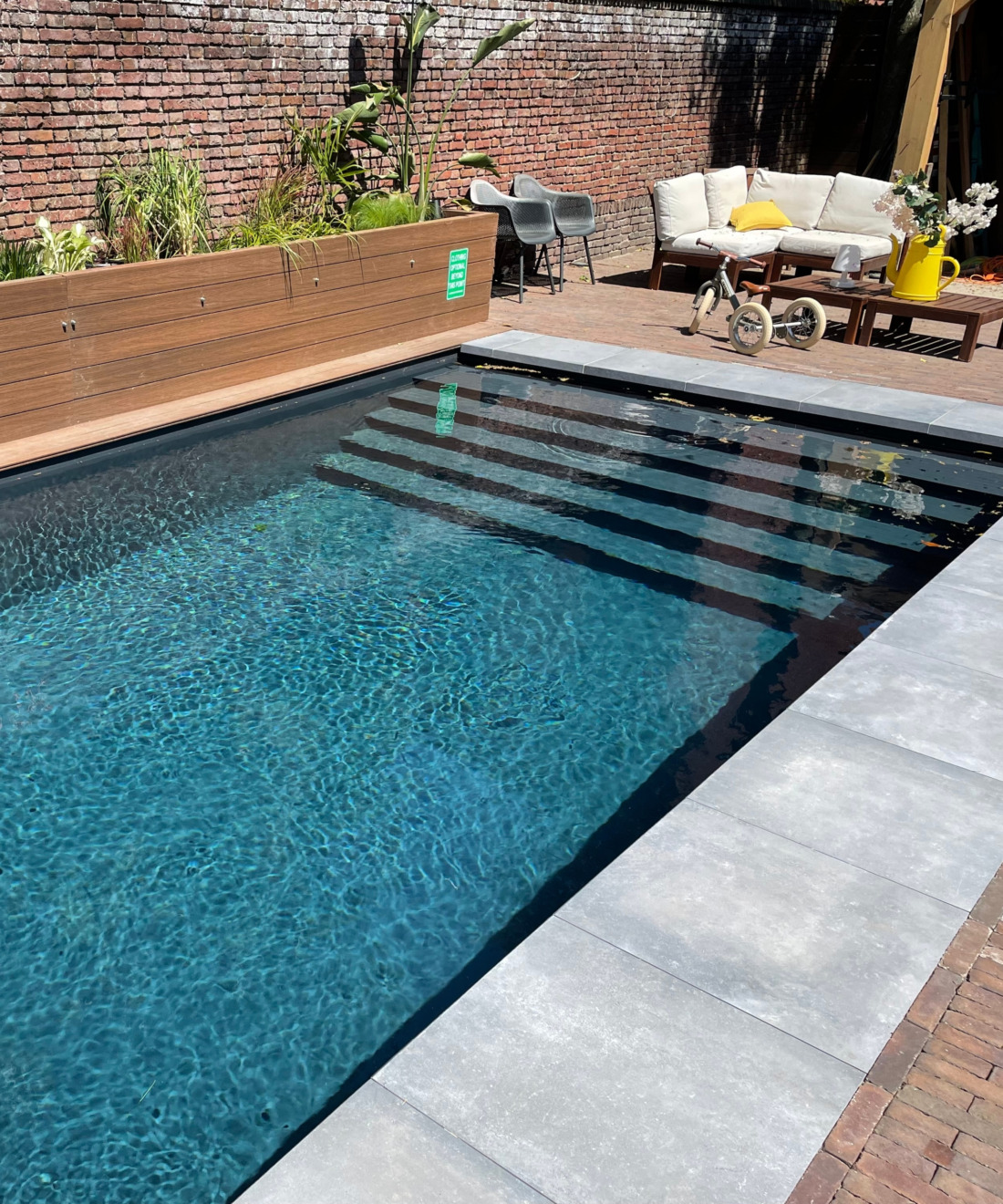 Gezellige, omsloten stadstuin met een sfeervol zwembad, een oude bakstenen muur en een comfortabele loungehoek.