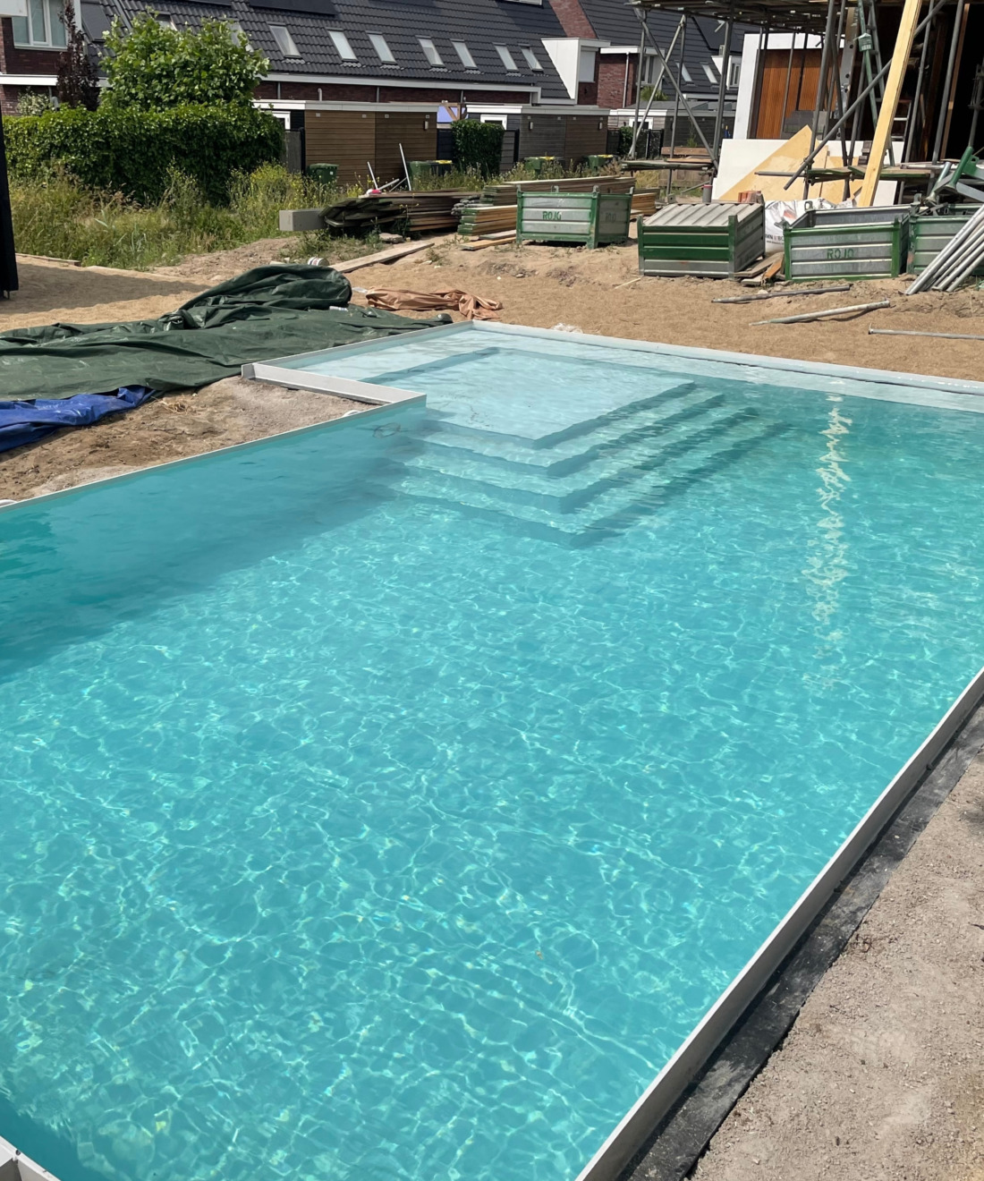 Wit HDPE zwembad aanleggen in nieuwbouwtuin, plaatsing HDPE kuip met plage en trap.