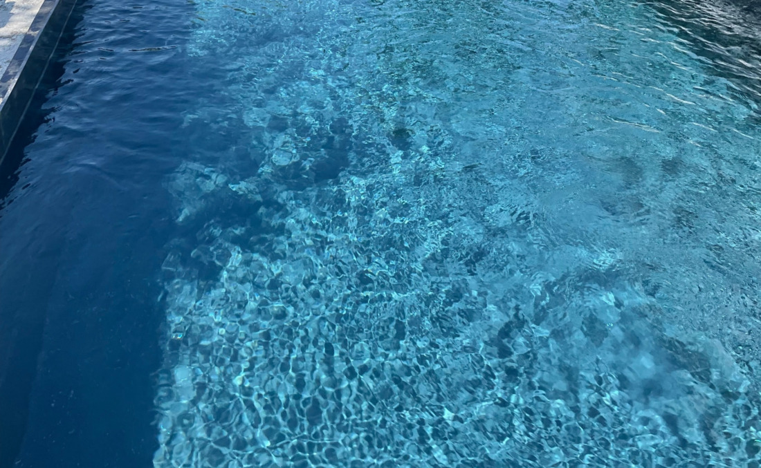 Close-up van helder zwembadwater met lichtreflecties op de bodem van een donkere JDL HDPE zwembadkuip.