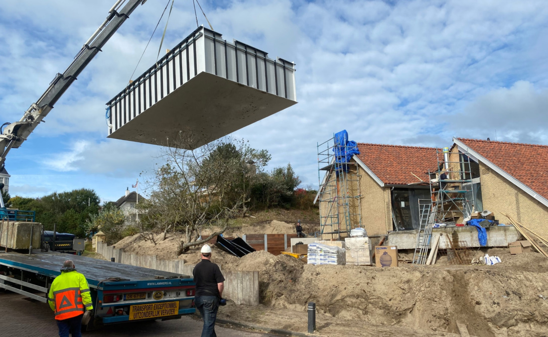 Plaatsing van een wit prefab HDPE zwembad van JDL, dat met een grote telescoopkraan over de bouwplaats wordt gehesen.